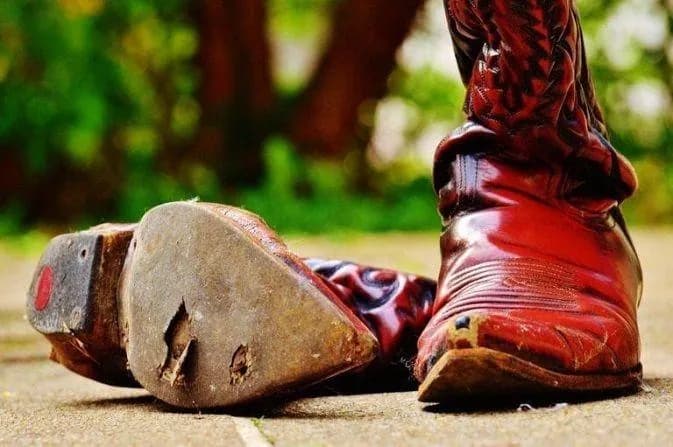 Đôi boot da mòn nặng ở đế và gót sau nhiều năm sử dụng