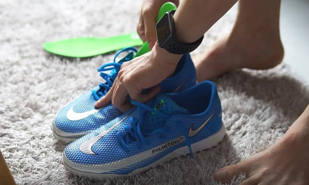 A wearer putting on new football boots while getting used to them at home