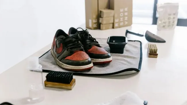 Sneakers laid out with a brush set and cleaning solution before a wash