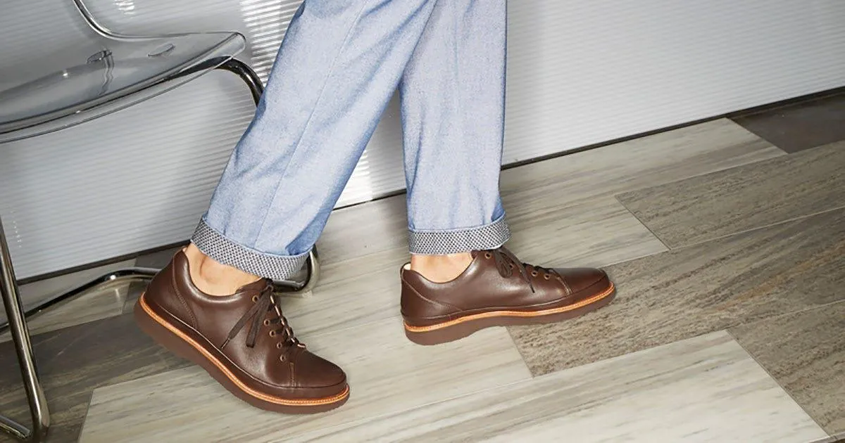 Brown lace-up leather shoes mid-step, the toe flexing with each stride