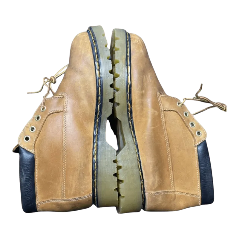 Đôi boot Dr. Martens màu nâu vàng với đế giày bám bẩn và dây giày lộn xộn trước khi vệ sinh.